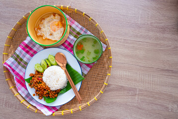 Thai food of Original spicy fried basil with pork served with rice , fried egg and soup Served in Thai style on bamboo tray.