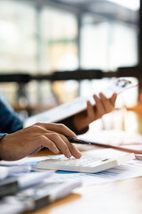 ..Asian male finance staff is pressing a calculator to calculate company sales and profit to report her boss, profit calculation idea. And the company's performance...