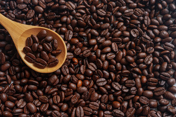 Roasted Coffee beans on wooden spoon with roasted coffee beans background
