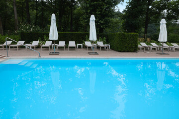 Many sunbeds and umbrellas near outdoor swimming pool