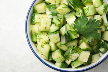 Bowl of delicious cucumber salad on light table, top view