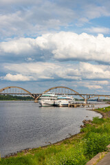 RYBINSK, RUSSIA - JULY 9, 2022: Volzhskaya embankment with cruise ships and Rybinsky bridge. Provincial russian city in summer day.