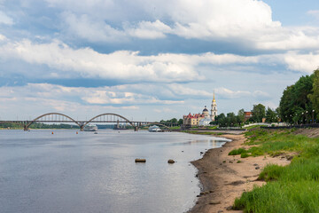 Fototapeta premium Volzhskaya embankment with tourists and Rybinsky bridge. Provincial russian city in summer day.