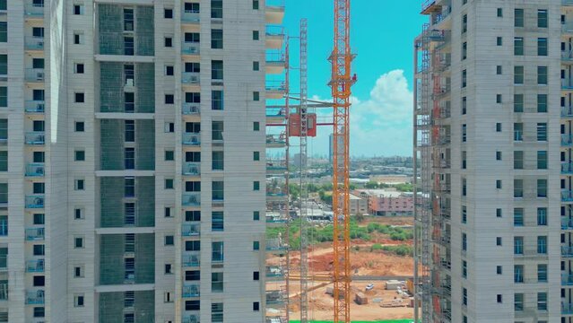 Zoom effect, freight elevator at the construction site of high rides up and down. A freight construction elevator rises to the top of a skyscraper. A temporary elevator is being built in the building