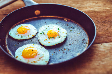 fried eggs, scrambled eggs in a frying pan with seasonings and spices, on a wooden table, close-up, rustic style, farm