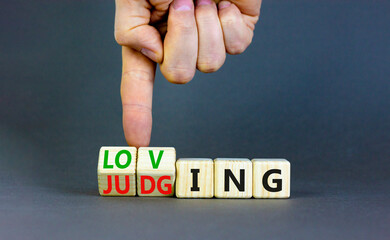 Loving or judging symbol. Concept words Loving or Judging on wooden cubes. Businessman hand. Beautiful grey table grey background. Business loving or judging concept. Copy space.