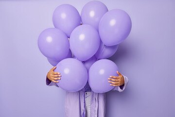 Faceless woman hides behind bunch of balloons celebrates special occasion prepares decoration for...