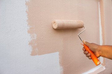 Roller painting wall with hand