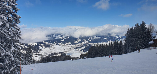 Panorama of the snowy Alps and view of the ski runs from the Griessenkareck peak near Flachau in Austria on a sunny winter day.