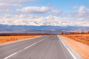 Beautiful landscape road in autumn forest with snow peaks mountains Chuysky tract, Altai Kurai steppe Russia.