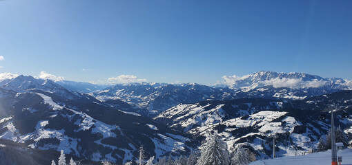 Fototapeta premium Panorama of the snow capped Alps and the view from the Griessenkareck summit near Flachau in Austria, on a sunny winter day.