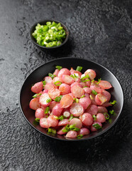 Roasted radish with spring onion and herbs in a black bowl