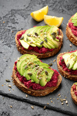 Avocado, beetroot hummus toast on dark sourdough bread topped with pumpkin, sunflower, hemp and flaxseed. Vegan, vegetarian super food