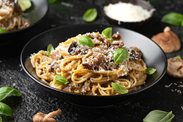 Porcini and woodland mushrooms pasta with pecorino cheese, basil in black bowl