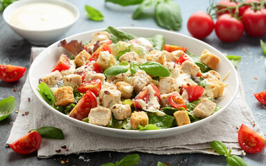 Vegetarian ceasar salad with meat free chicken pieces cherry tomatoes croutons and lettuce in white plate.