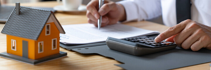 businessmen using a calculator calculating house tax refund on the table, an Accountant calculating...