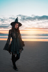 young latin woman dressed as a witch walking on the shore of the beach portrait