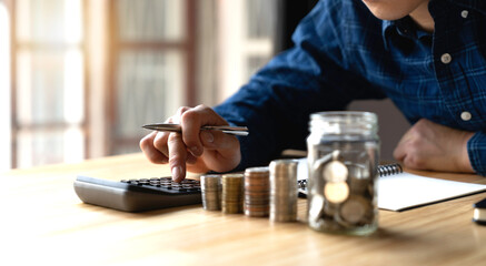 Tax and savings finance concept, businessmen saving money concept. hand holding coins and putting them in jug glass.