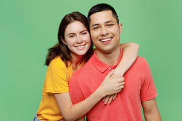 Young smiling lovely fun adorable couple two friends family man woman 20s wear basic t-shirts together girlfriend hug boyfriend isolated on pastel plain light green color background studio portrait