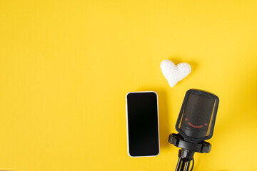 Microphone, smartphone and a white heart on a yellow background with a space for text.
