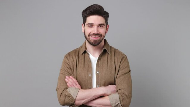 Young smiling satisfied happy fun cool cheerful caucasian man 20s he wear brown shirt look camera aside on workspace area isolated on plain grey background studio portrait. People lifestyle concept