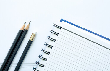 black pencil and notebook on white background,Top view of two kraft spiral notebook and black pencil 