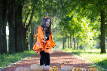 Obraz premium Child girl als little cute witch with pumpkin outdoors in halloween