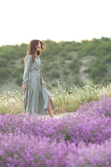 Fototapeta na wymiar Beautiful woman with long dark hair in a dress in a lavender field.