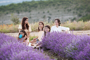 Portrait of a mother with her daughters on a background of lavender, Cozy picnic in a lavender...