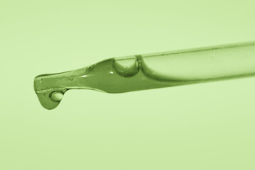 Pipette with aloe vera essence, juice from the plant on a green background. Cosmetic concept....