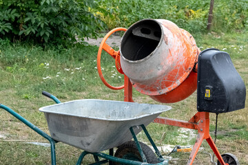 A concrete mixer and a wheelbarrow on a construction site