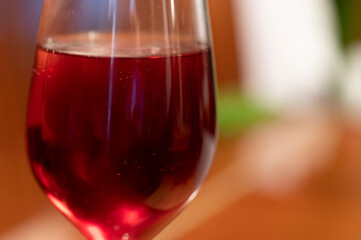 Wine glass with red raspberry juice, cut with water on orange ple with an accent of green - an interesting background
