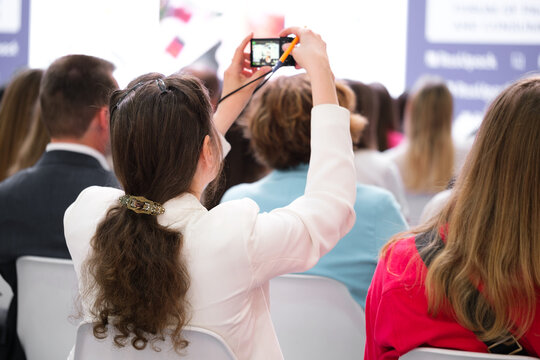 Business woman at a business conference or presentation or training shoot video on smartphone