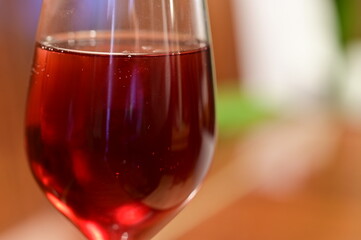 Wine glass with red raspberry juice, cut with water on orange ple with an accent of green - an interesting background