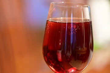 Wine glass with red raspberry juice, cut with water on orange ple with an accent of green - an interesting background