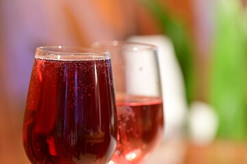 Wine glass with red raspberry juice, cut with water on orange ple with an accent of green - an interesting background