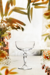 Empty champagne cocktail glass on table with autumn leaves frame, front viewyellow