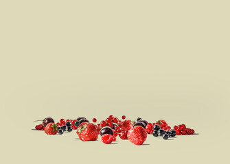 Various fresh fruits and berries scattered over a beige background.
