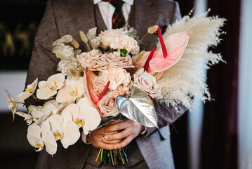 Man holding bouquet of roses. Handsome man in an elegant suit giving a huge blooming bouquet...