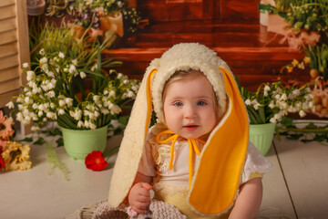 portrait girl one year old in a bunny costume shooting in the studio in the background flowers wooden background dekor 