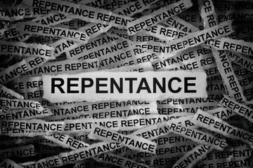 Strips of newspaper with the words Repentance typed on them. Black and white. Close up.