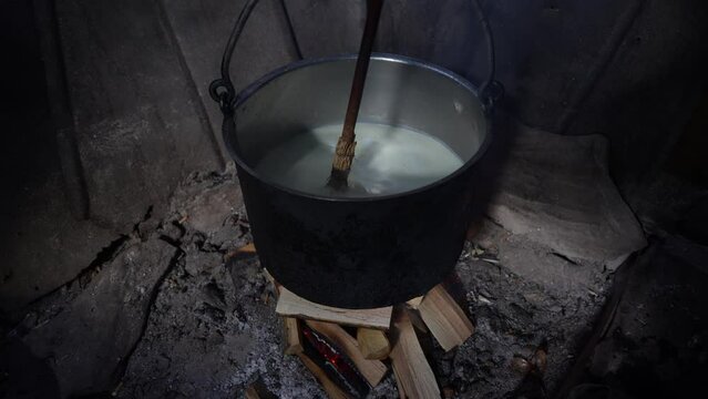Making organic sheep cheese in wooden mountain Carpathian cheese factory with a boiling smoked cauldron with milk on open fire, Western Ukraine, Europe