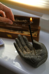A match in the palms ignites an incense stick