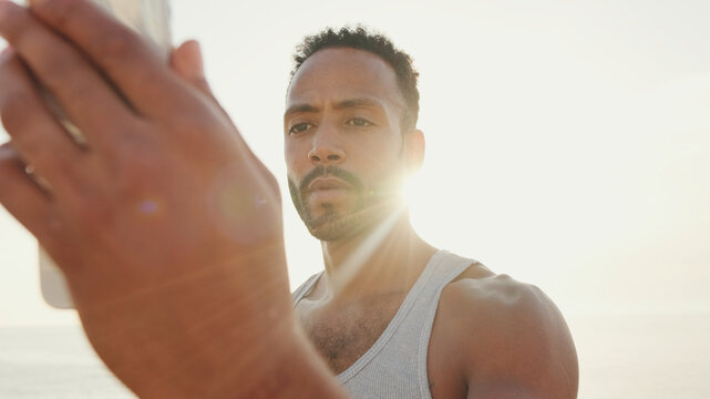 Close Up, Young Bearded Male Toned Athlete Uses Cell Phone While Resting After Training On The Embankment