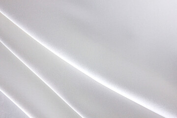 The luxury of white fabric texture background. Closeup of rippled white silk fabric. Abstract cloth or liquid wave background. Cloth soft folds. Creases of satin, silk, and cotton.