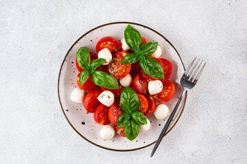 Italian caprese salad with sliced tomatoes, mozzarella, basil, olive oil on a dark background. Top view. Italian food. Healthy salad. Summer food