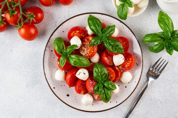 Italian caprese salad with sliced tomatoes, mozzarella, basil, olive oil on a dark background. Top view. Italian food. Healthy salad. Summer food