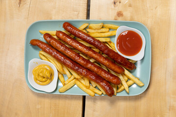 Grilled sausages served with french fries with dips on a plate