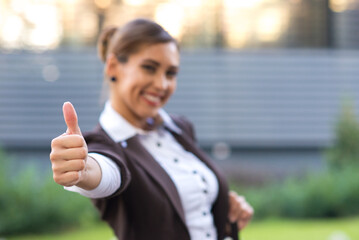 Young smiling businesswoman showing thumbs up