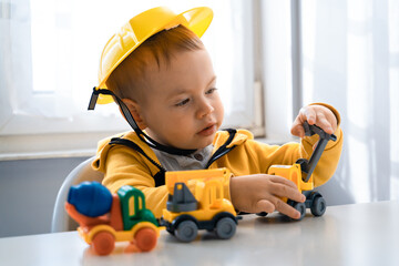 Fototapeta na wymiar Child play with construction machinery at home, dreams to be an engineer. Little builder. Education, and imagination, purposefulness concept. Boy with digger